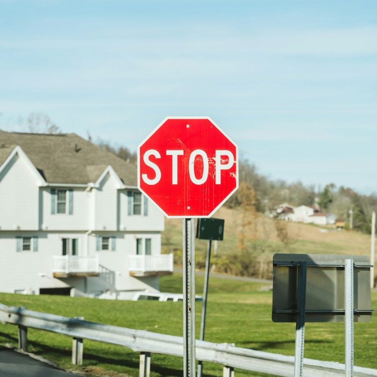 Señal de tráfico octagonal roja con la palabra "STOP" en un entorno rural.
