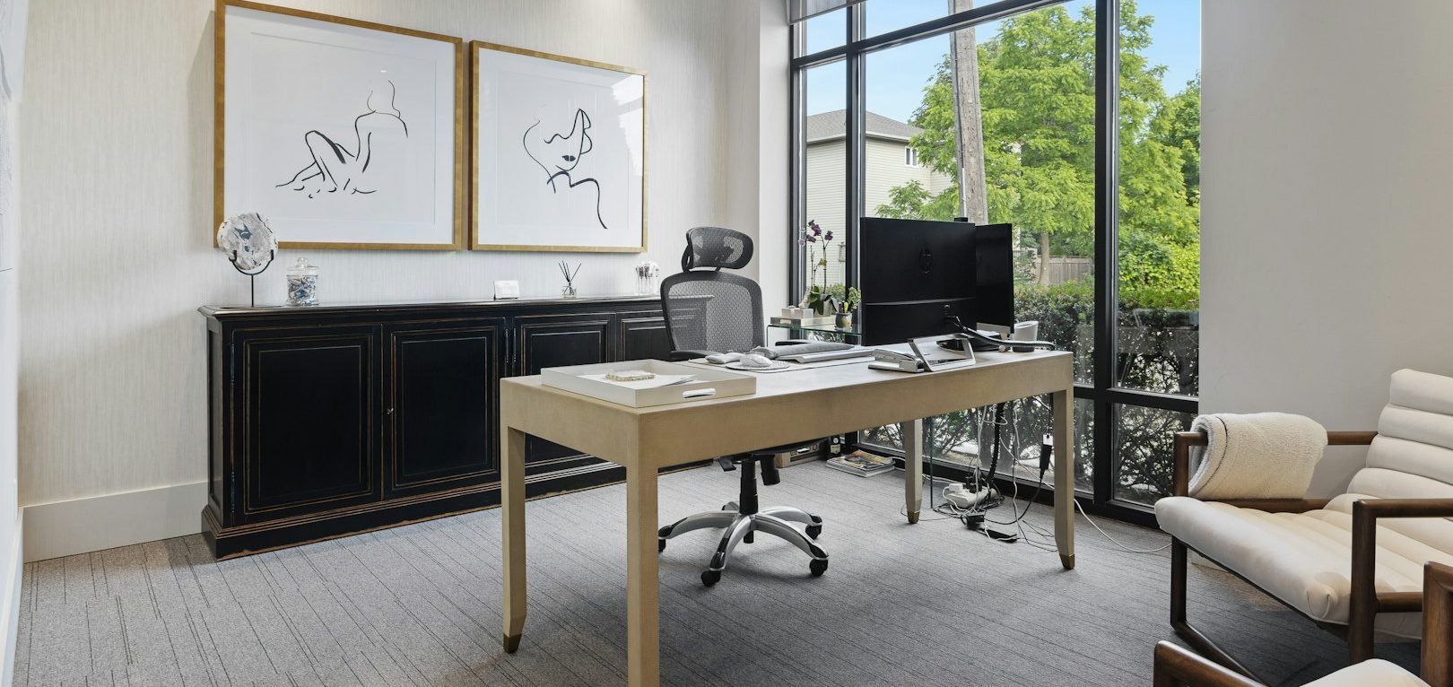 Oficina moderna con escritorio, ordenador y grandes ventanales que ofrecen luz natural.